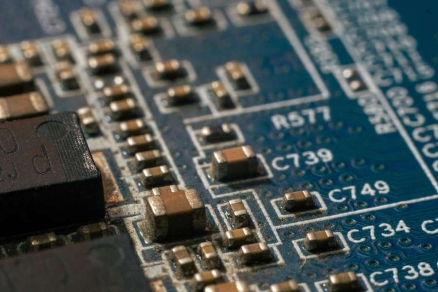 Gros plan sur une carte mère bleue avec des condensateurs dorés et des références de composants gravées, signes que le hardware a besoin d'être mis à jour.